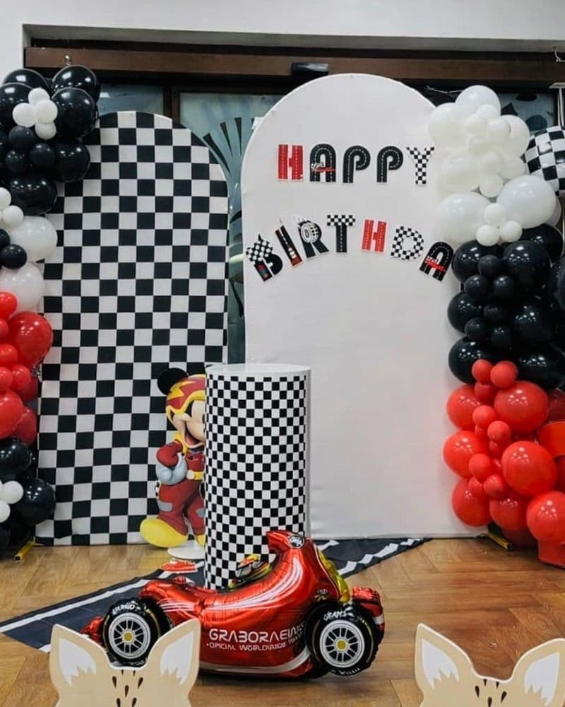 Черно-бяла раирана арка с състезателни коли и надпис Happy Birthday